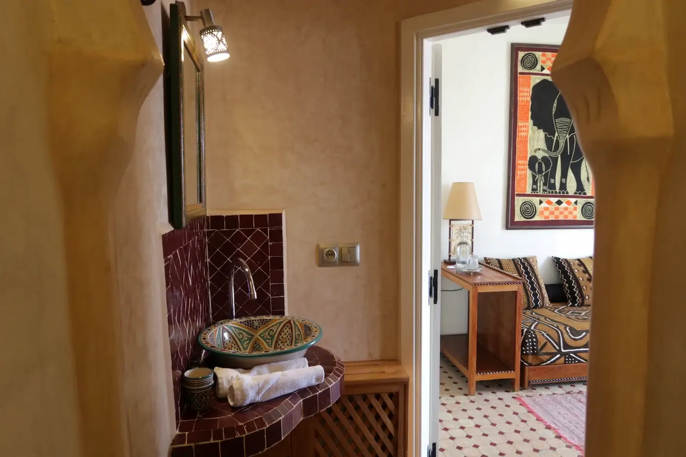 Bathroom entryway in the Junior Suite of Kasbah Rose guesthouse, featuring traditional Moroccan archway and decorative tilework leading to the elegant bathroom facilities